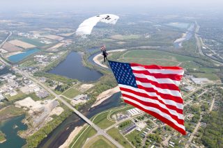 Skydiver on a demonstration jump carrying a huge, billowing American flag.