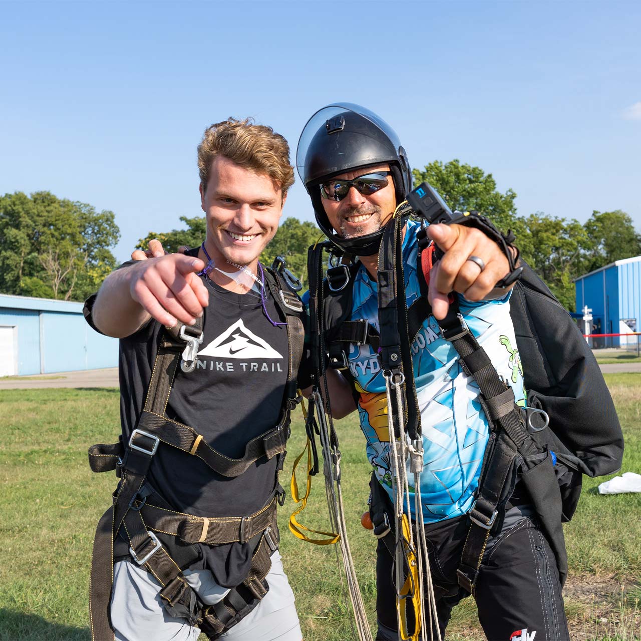 Shortly after landing from skydiving in Dayton a tandem instructor and student smile and pose for a photo
