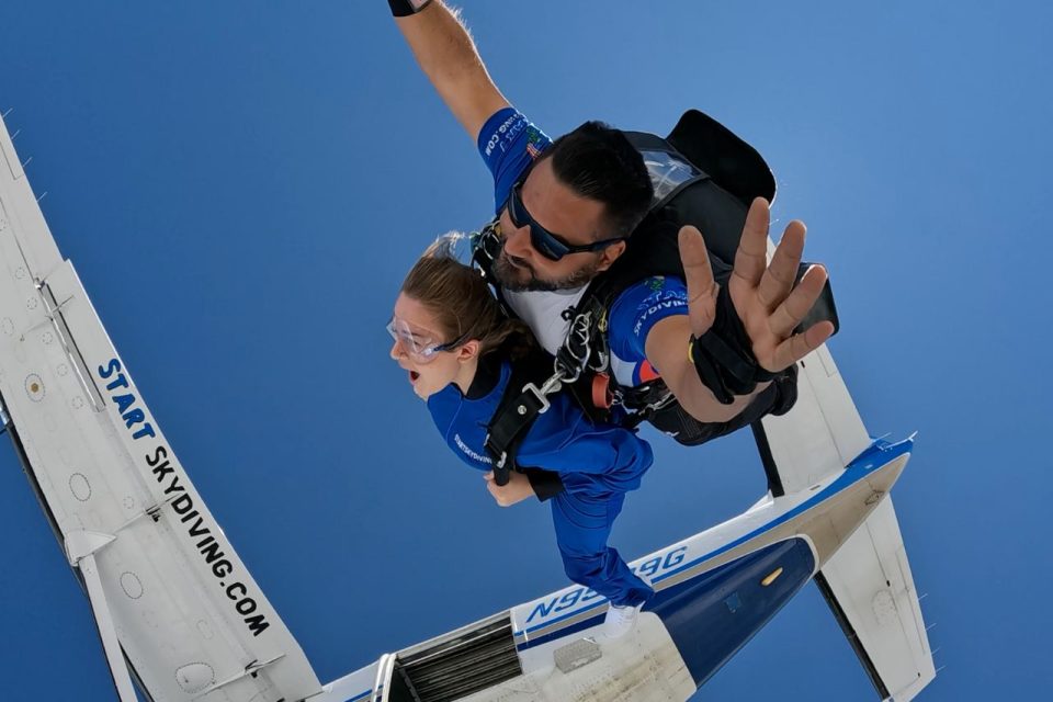 A female tandem student in a blue jumpsuit and her instructor moments after exiting the Caravan at Start Skydiving