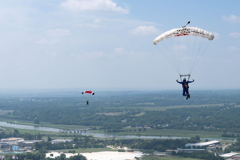 Two skydivers fly beneath their parachutes taking in the views