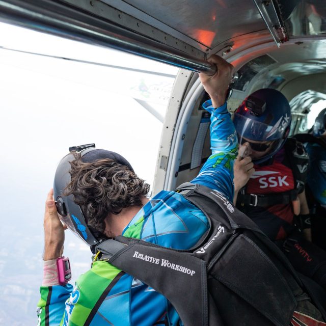 A licensed skydiver looks out of the open door of the aircraft to check the spot before the pilot gives the greenlight to exit