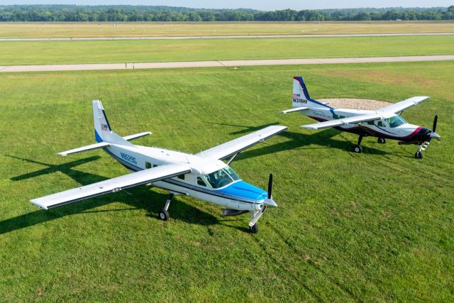 Start Skydiving's Cessna 208 Grand Caravan and Cessna 208B parked in the large, spacious grass landing area at Start Skydiving