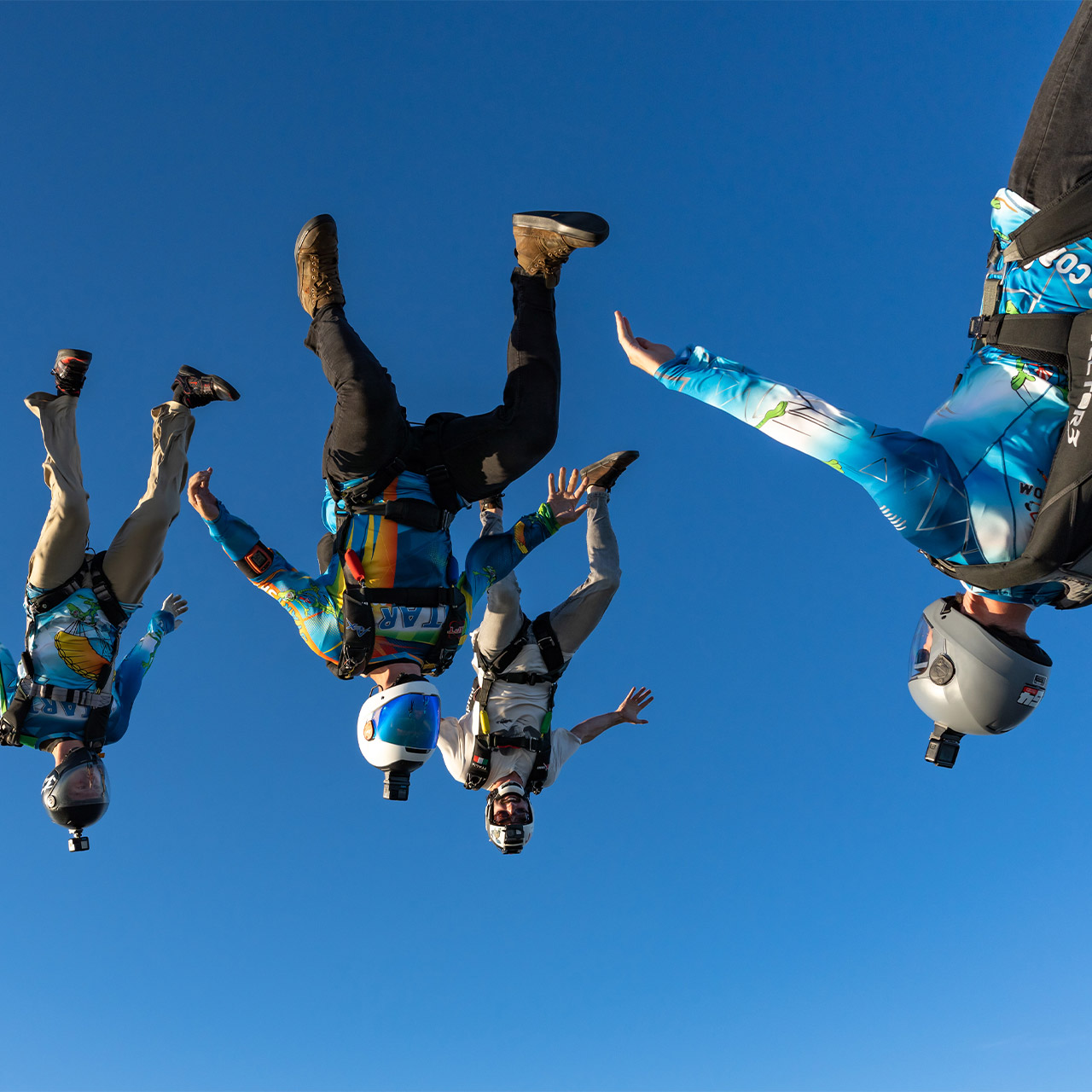 Four licensed skydivers in freefall flying a steep angle