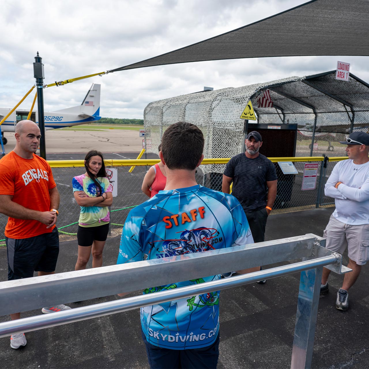 A group of learn to skydive AFF students listen closely as an AFF Instructor teaches them during a first jump course
