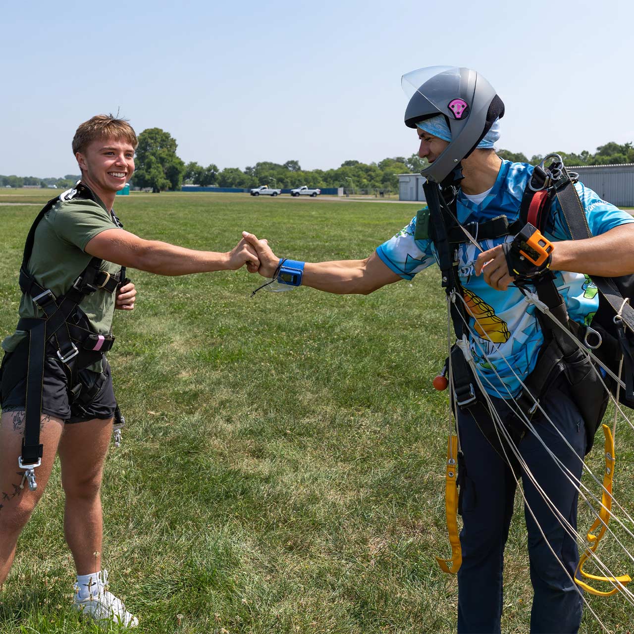 Tandem skydiving student and their instructor fist bumping after landing.