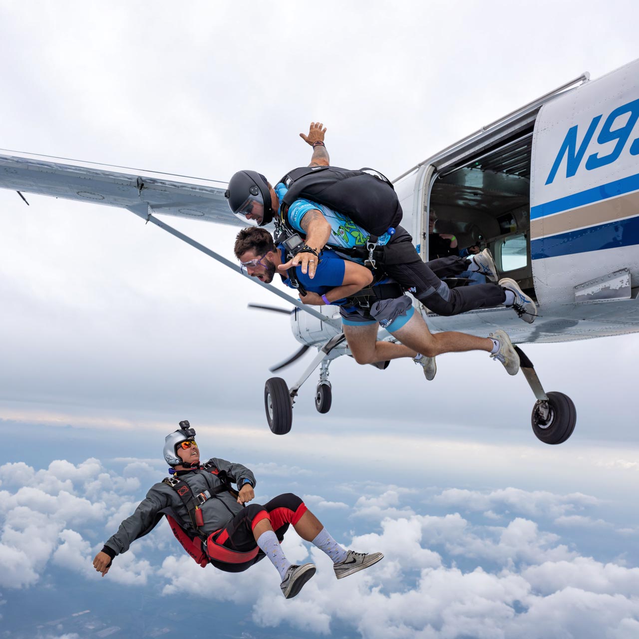 Tandem instructor and student exiting the aircraft while their talented videographer backflies beneath them to get the perfect shot