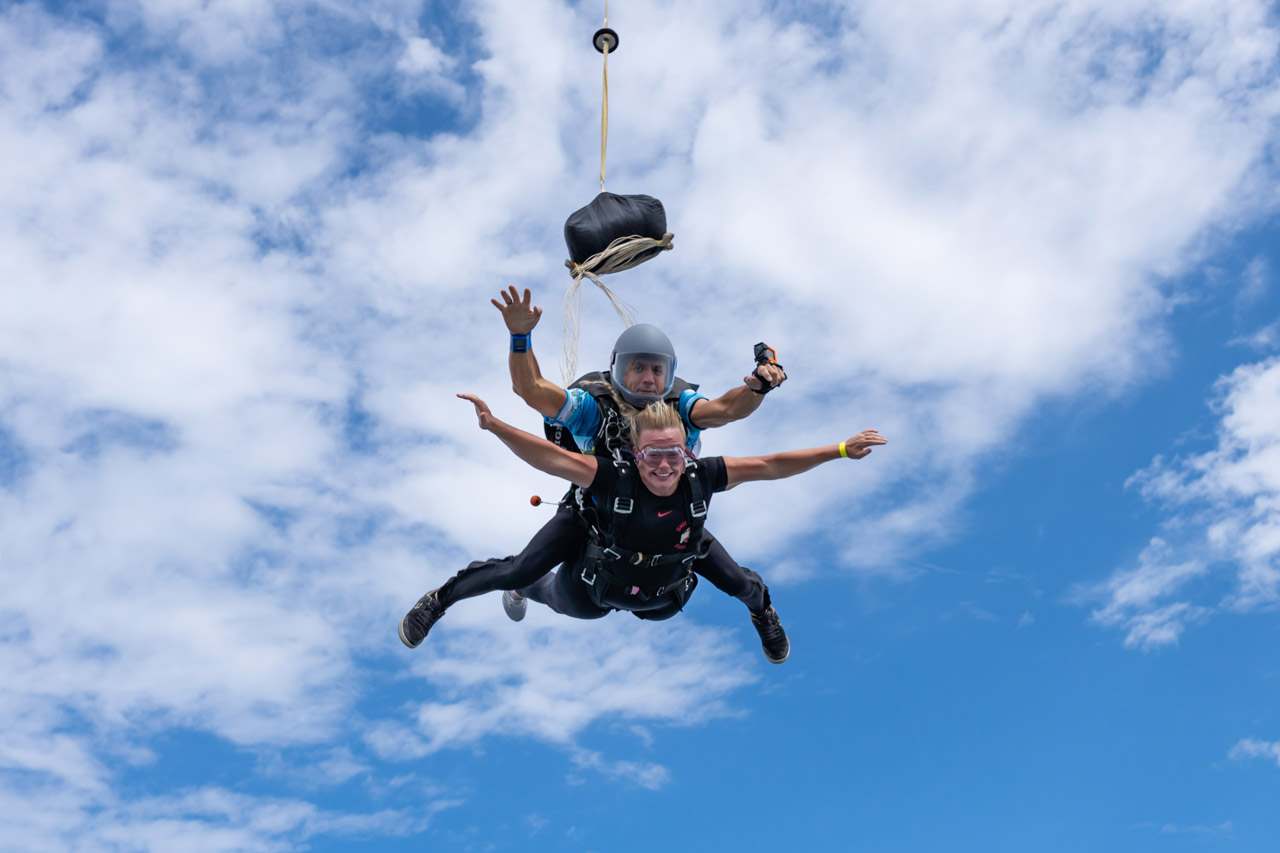 A blonde female tandem student and her tandem instructor moments after he begins the deployment process.